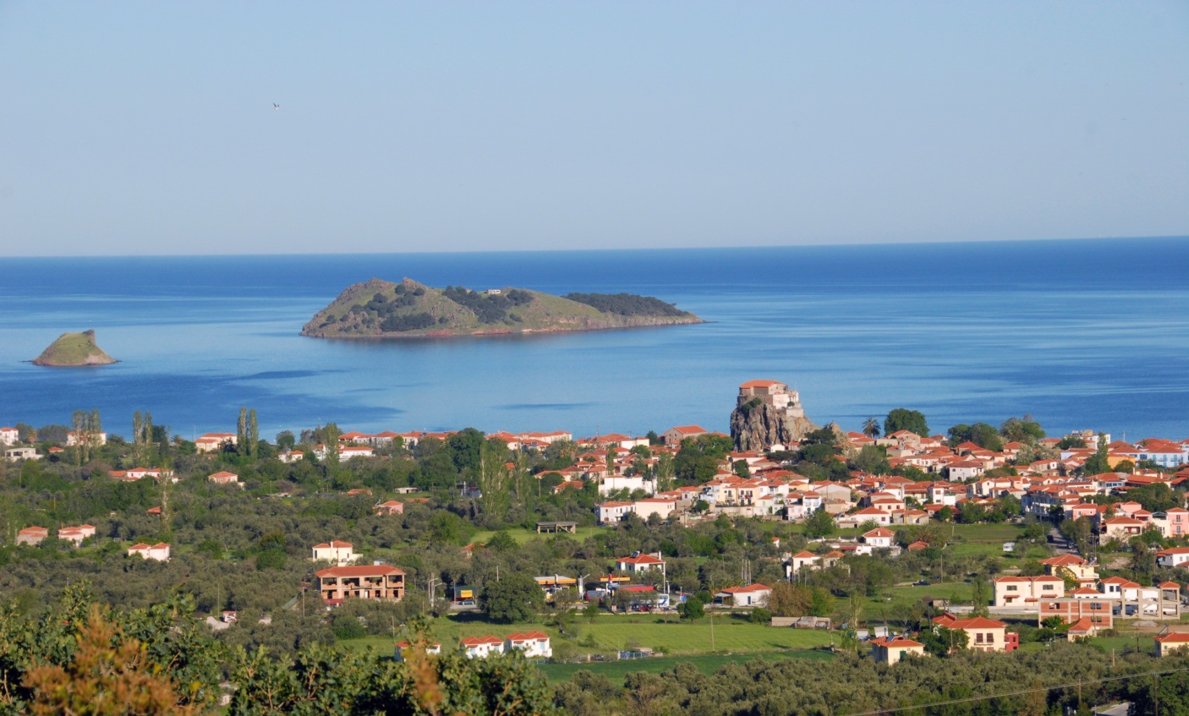 Whitewashed apartment complex on a green hill above the sea